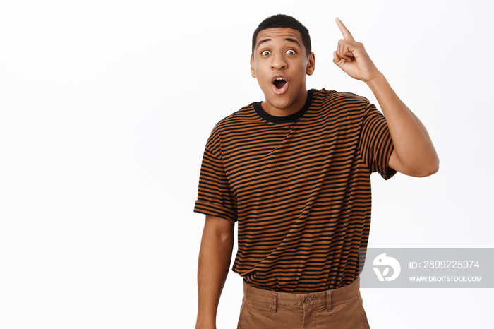 Excited African american man pointing up, looking amazed, pitching an idea, found smth, standing over white background