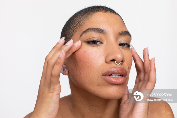 Studio portrait of woman with nose ring touching face