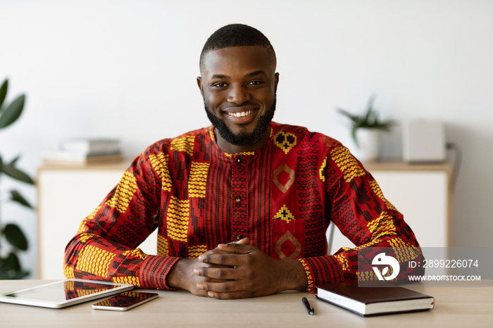 Handsome African Freelancer Man In Traditional Costume Sitting At Desk In Office