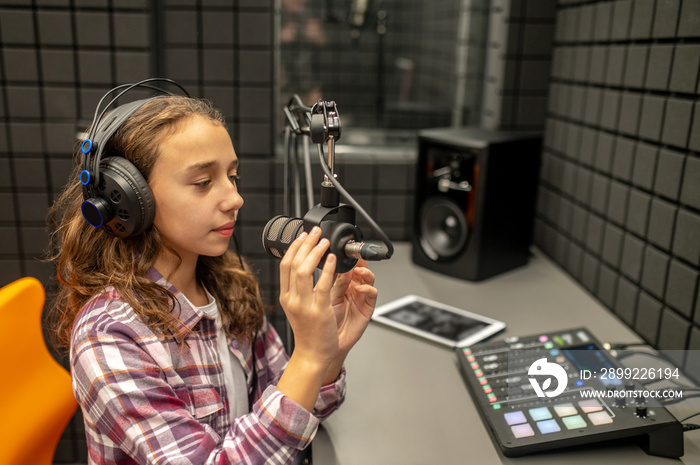 Teenage girl checking her mike before recording a podcast