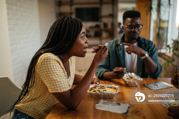 Black friends eating take out food at home