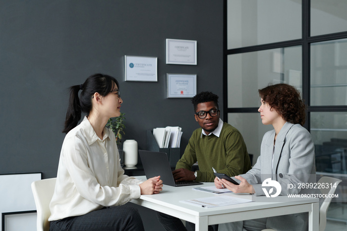 Two managers sitting at table and talking to candidate during job interview