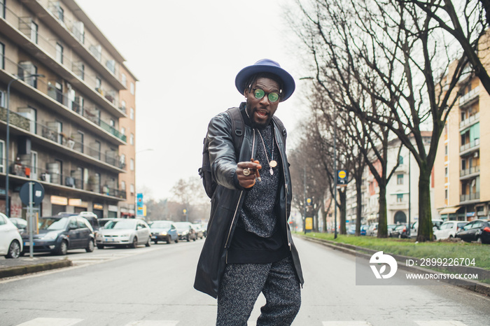 portrait of young african man standing in the street and smoking cigar