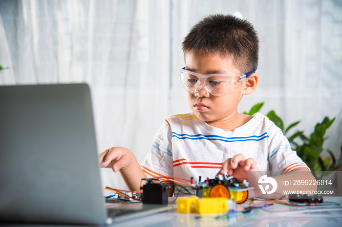 Asian kid boy assembling wheel into Arduino robot car homework, Little child trying assemble build wheel to car toy, creating electronic AI technology workshop online school lesson