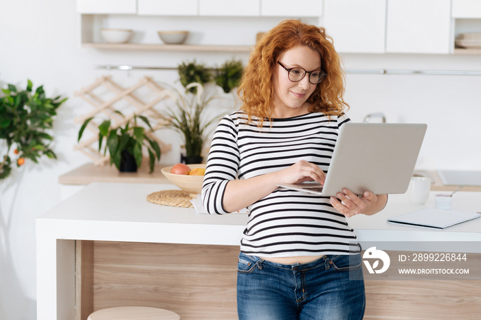 Smiling pregnant women looking at laptop and working