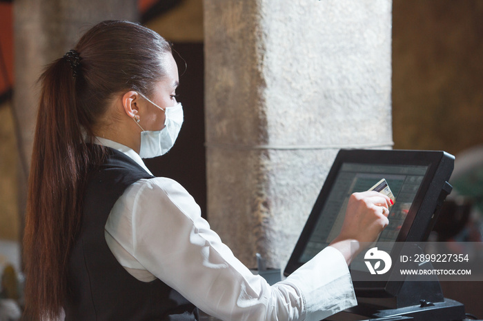 work of a waiter in a restaurant in a medical mask.