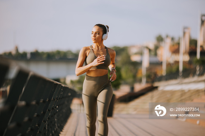 Active young beautiful woman running on the promenade along the riverside