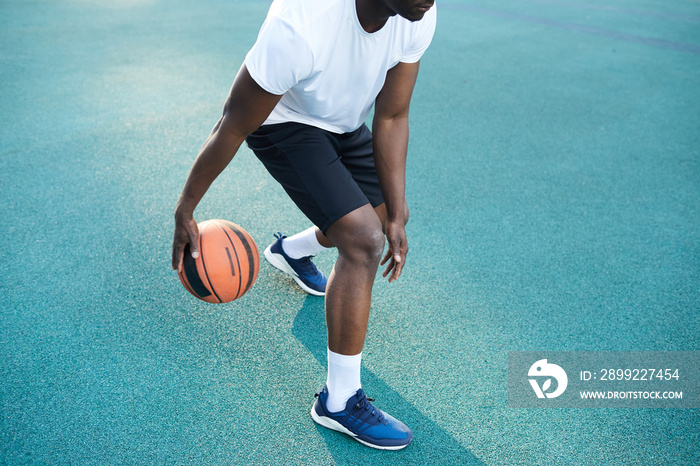 Action shot of unrecognizable African man playing basketball outdoors, copy space