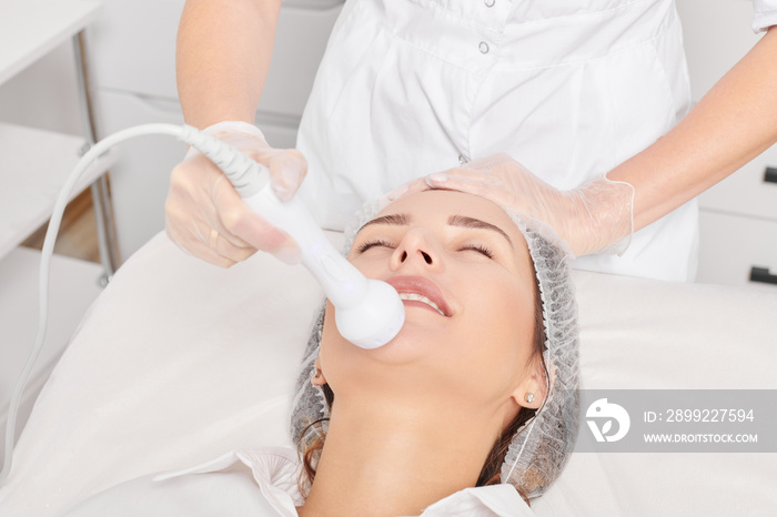 Cosmetologist makes RF lifting for rejuvenation woman face, anti aging cosmetic procedure