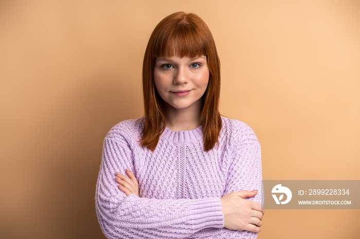 Positive ginger woman standing with crossed arms and charming smile, expressing confidence