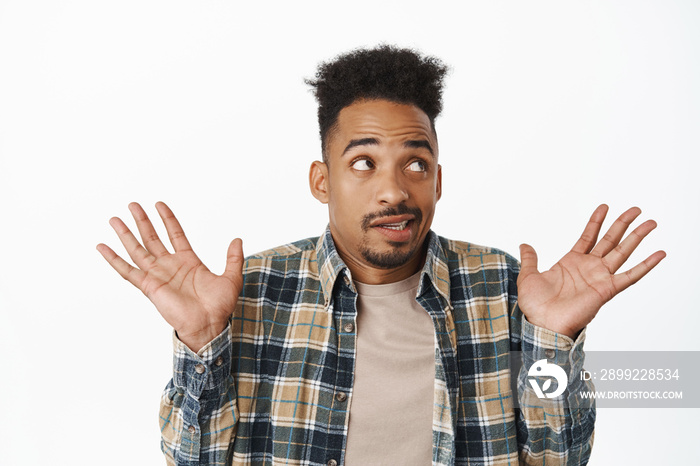 I know nothing. Funny african american man raising empty hands up and looking away, avoiding eye contact acting innocent, hiding smth, dont know what to say, standing clueless over white background