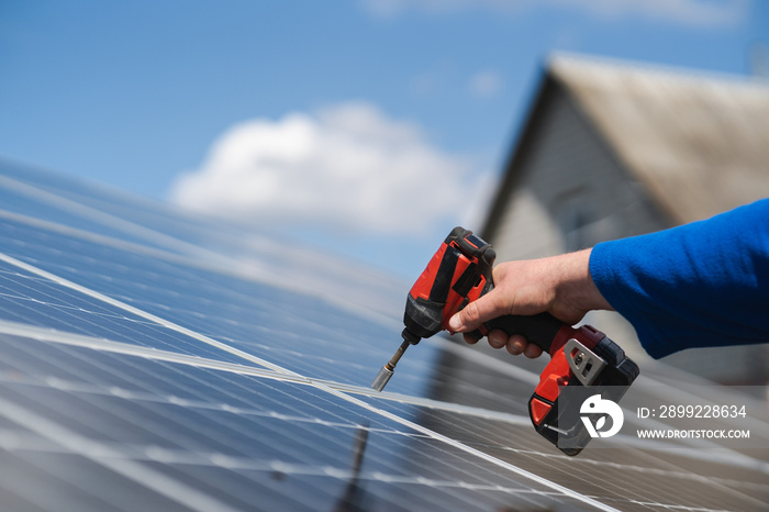 Close-up of engineer’s hand with a drill screwdriver repairing a solar panel