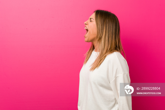 Young authentic charismatic real people woman against a wall shouting towards a copy space