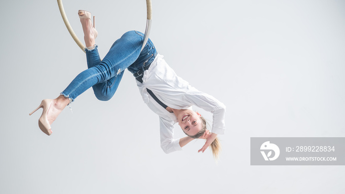 Caucasian woman in casual clothes on an aerial hoop.