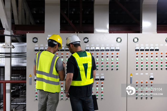 Electrical Engineer team working front HVAC control panels, Technician discussion and training daily check controls system for security functions in service room at factory.