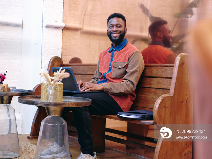 UK, London, Smiling businessman using laptop in creative studio