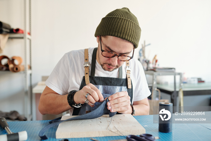 Sewing leather in workshop