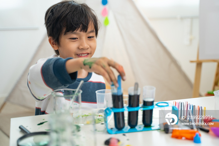 Boy making chemical experiments, learning mixing water paint colors