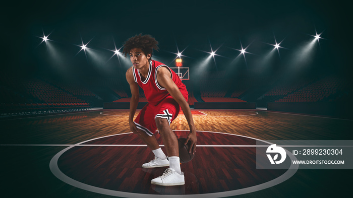 Young African American boy with basketball in the middle of the stadium