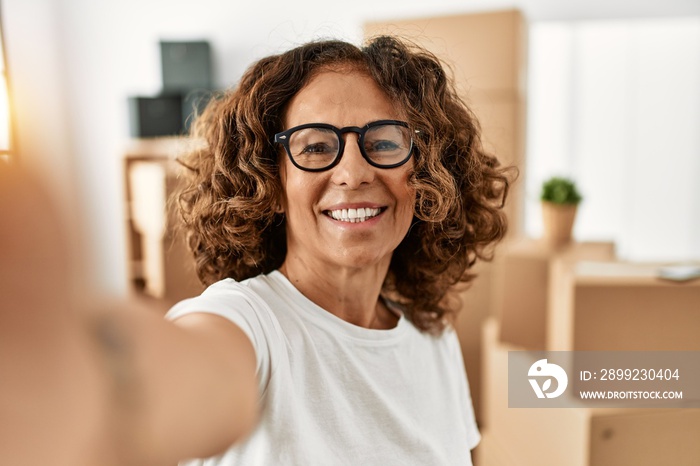 Middle age hispanic woman smiling confident make selfie by the camera at new home