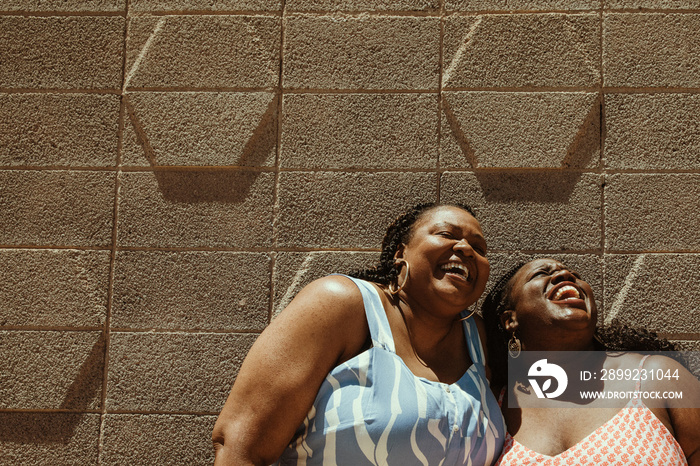 closeup of 2 plus size African American women’s faces laughing