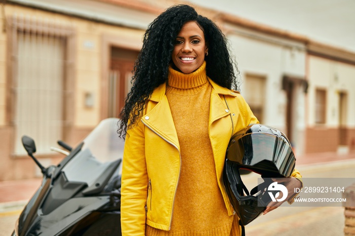 Middle age african american woman holding motorcycle helmet at the city.