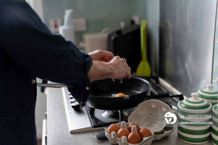 Close-up of man breaking egg into pan