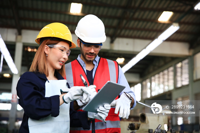 Supervisor and engineer wearing safety unform and equipment disucsion at work shop or factory