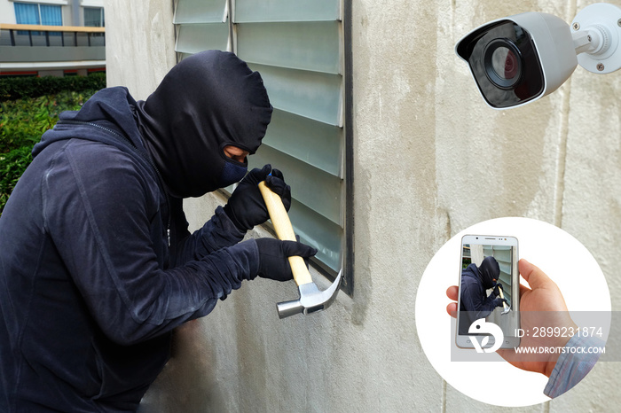 Surveillance Camera capture and record caught Masked thief with hammer and hand holding Mobile Phone Detecting on application, home Security System