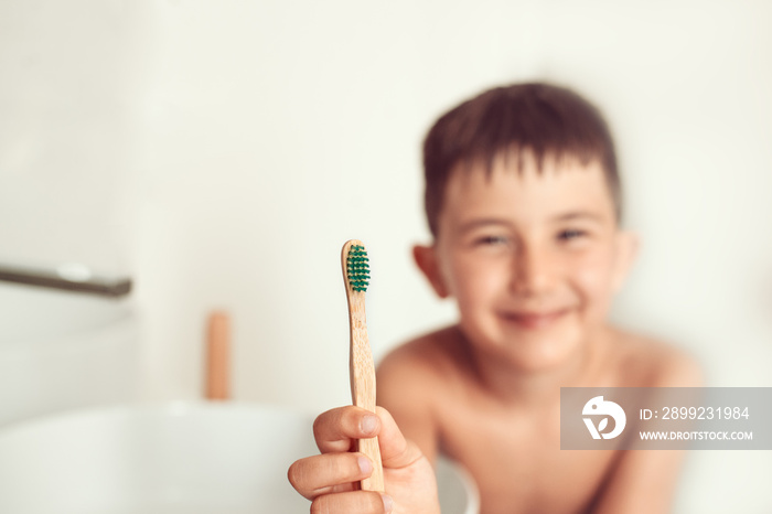 The child brushes teeth with a bamboo toothbrush.