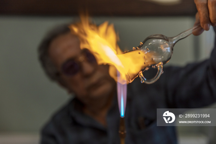 Close up macro of glass blower working with flame on a handmade wine glass from precious crystal in a workshop. Concept of handmade, high quality, artisan, made in Istanbul, Turkey, glass blowing.