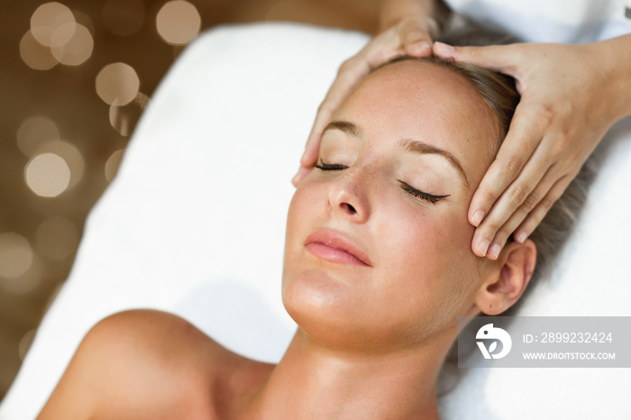 Young woman receiving a head massage in a spa center.