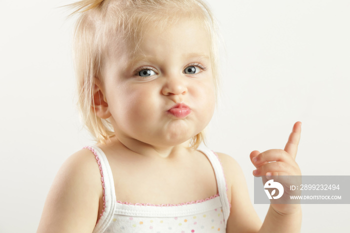 Studio portrait of an adorable blonde baby girl with an angry facial expression