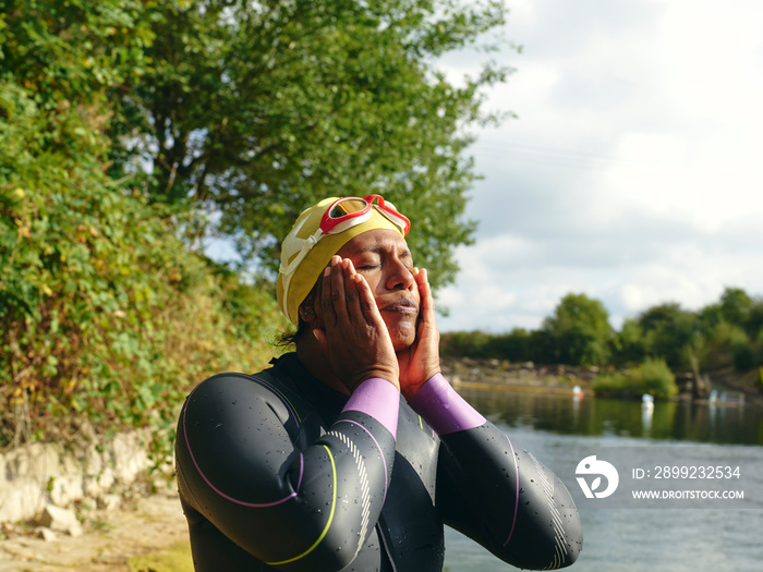 Woman in swimming cap and goggles massaging face