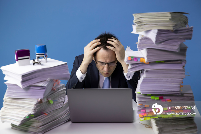 sad depressed exhausted office worker wrapping his hands around his head.