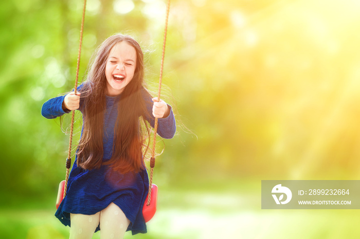 Cute little girl on a swing in the park. Fun, joy, freedom.