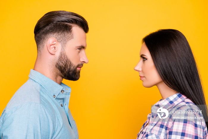 Profile portrait of jealous angry couple standing face to face having problem conflict isolated on vivid yellow background. Psychology concept