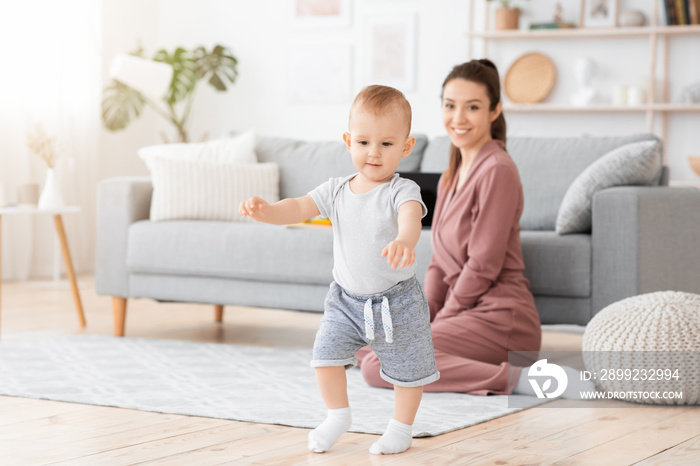 First Steps. Adorable smiling baby boy learning how to walk at home,