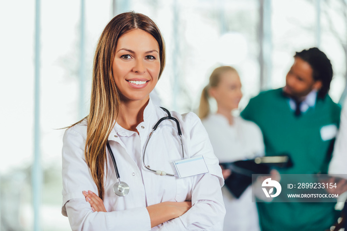 Portrait of attractive female doctor on hospital corridor looking at camera smiling.