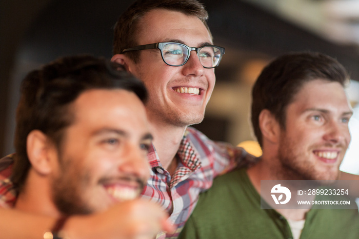 happy male friends watching football at bar or pub