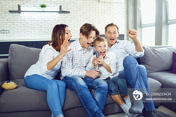 A happy family sings karaoke songs into the microphone in the room.