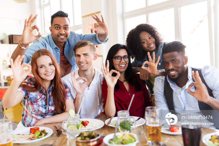 happy friends showing ok hand sign at restaurant