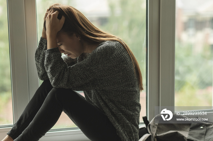 bullying in school, young woman cries at school because of harassment,discrimination and hatred of students of her peers