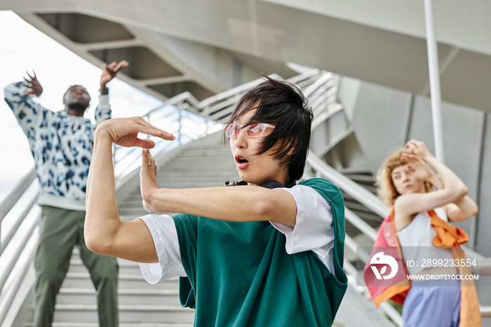 Diverse group of young people dancing outdoors and wearing street style clothes focus on Asian man in foreground