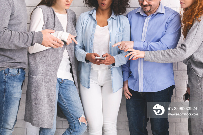 Group of millennials reaching hands to cellphone