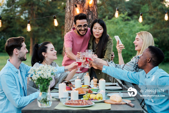 Group of intercultural cheerful friends gathered together by served table