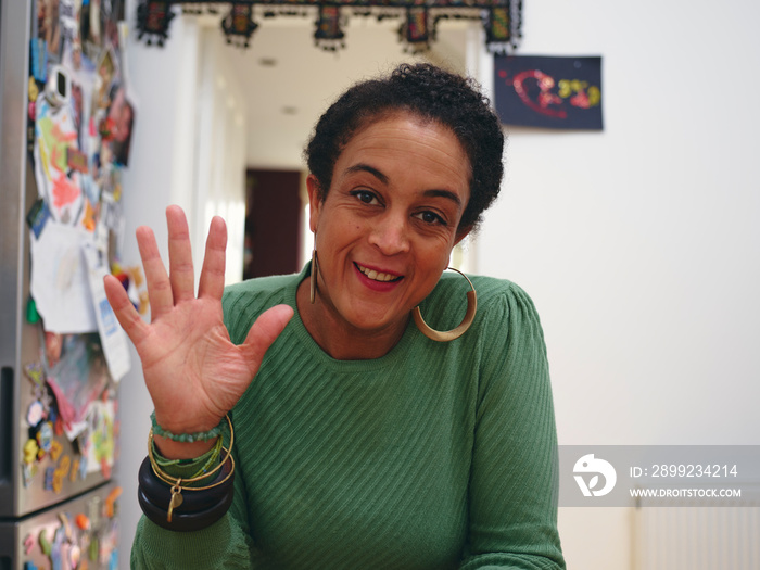 Portrait of woman looking at camera and waving hand