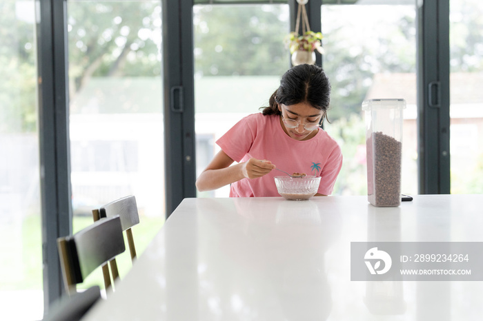 Girl eating breakfast at table in living room