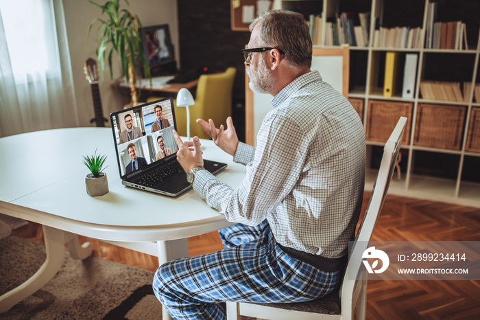 Male employee speaking on video call with diverse colleagues on online briefing with laptop at home.