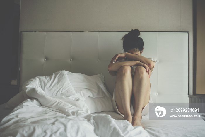 Portrait of depressed woman sitting alone on the bed in the bedroom. Conceptual of bad condition of broken hearted, sadness, loneliness woman.